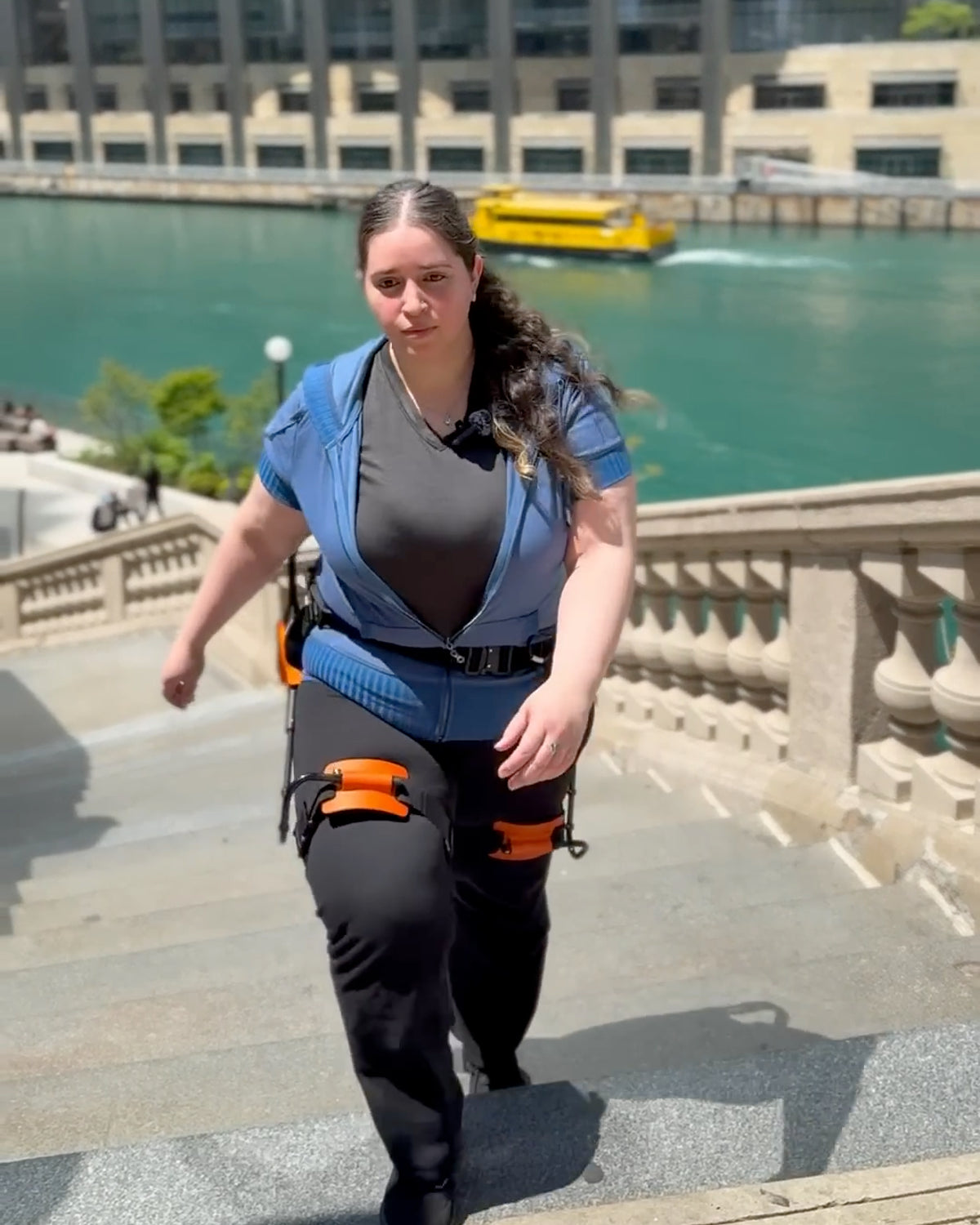 A woman is climbing up stairs wearing the first generation of RoboCT GoGo H exoskeleton.