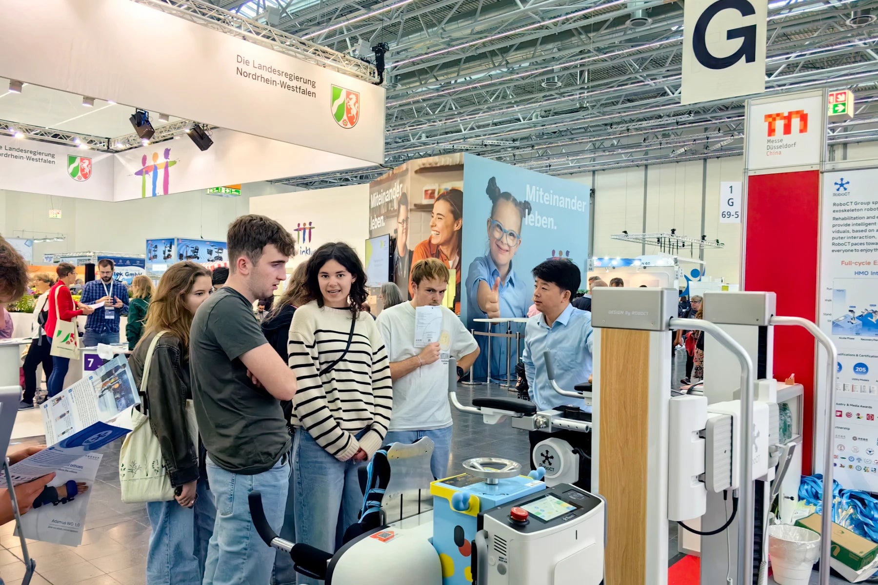 People interacting with RoboCT exoskeleton robot at an REHACARE 2024